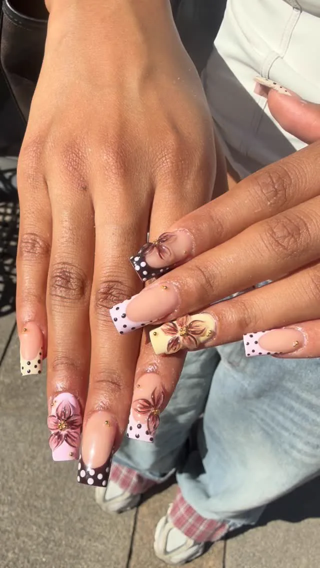 Roséfarbene Nägel mit Schleifen, floralen Details und schwarz-weißen Akzenten